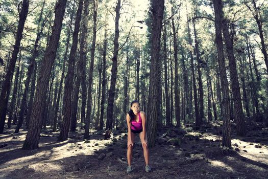 Runner relaxing after running in atmospheric enchanted forest. Beautiful woman model. 