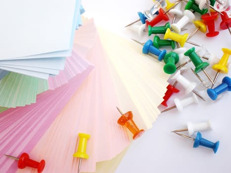 colorful sheets and push pins on white background