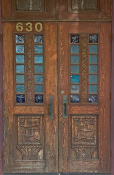 Old worn and weathered wood door with duck and bird carvings and etching