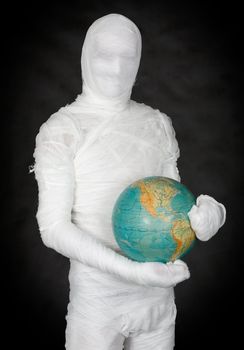 Man in costume mummy and terrestrial globe on black