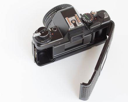 Vintage SLR camera with opened film door over white background