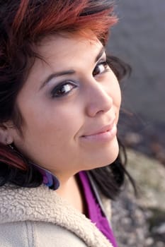 A young hispanic woman with red highlights in her hair by the sea shore.