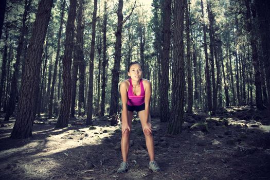 Woman running in forest. Female runner taking a break from running in beautiful forest with lots of mood / atmosphere and copy space. Beautiful young female athlete. 