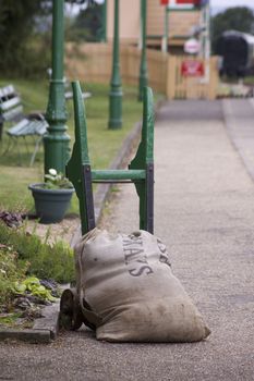 A retro platform trolly holding a hessian sack. Set on the platform at Harmans Cross, part of the Swanage Steam Railway network in Dorset.