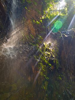 Tropical waterfall on a sunrays. A lot of water, drops and very wet.