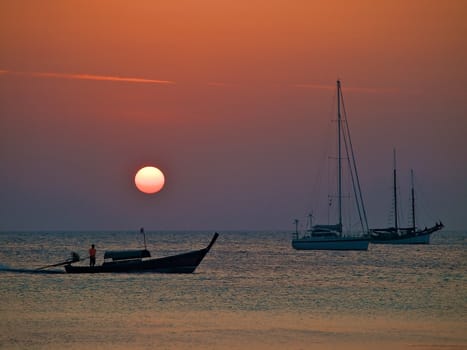 Tropical sunset with the anchored yachts silhouettes