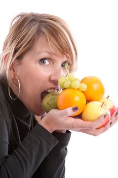 Pretty young blond woman about to take a bite out of the fruit in her hands