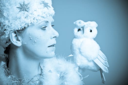 Beautiful woman wrapped in snowy clothing with a snow owl
