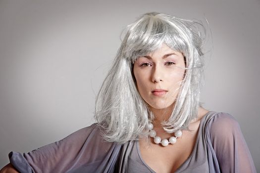 Beautiful woman with silvery wig on grey background