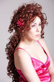 Beautiful girl with long red curly hair and a pink summer dress