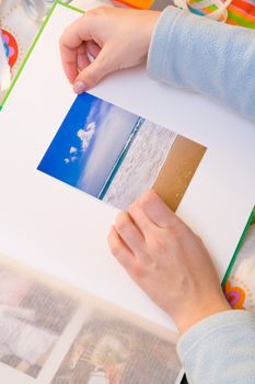 Woman hands sticking images in her photo album. Images can be replaced.