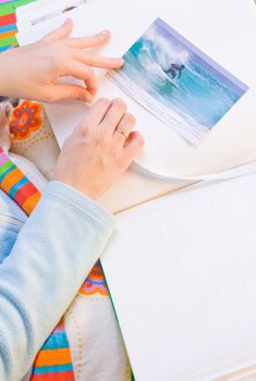 Woman hands sticking images in her photo album. Images can be replaced.