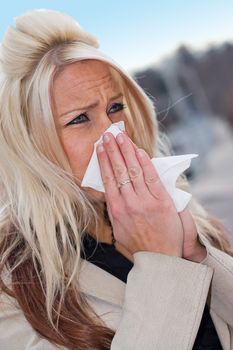 This young woman sneezing into a tissue either has a cold or really bad allergies.