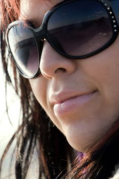 A young hispanic woman with red highlights in her hair and sunglasses.