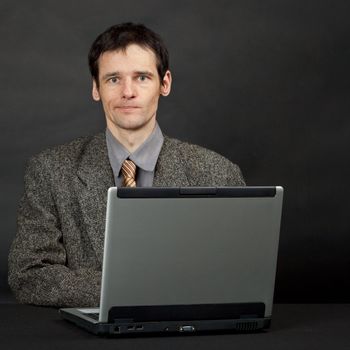 Funny young man sitting at a table with a computer