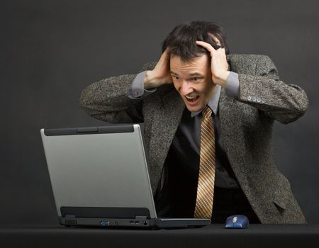 The young man shouts with despair looking at the computer screen