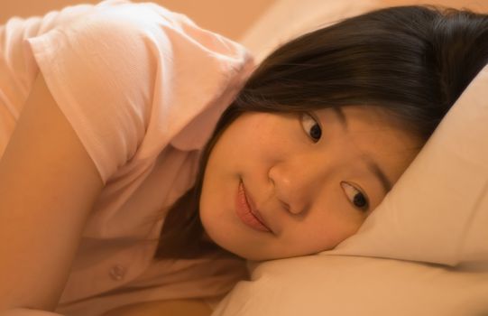 An asia beautiful woman is going to sleeping and watch something.