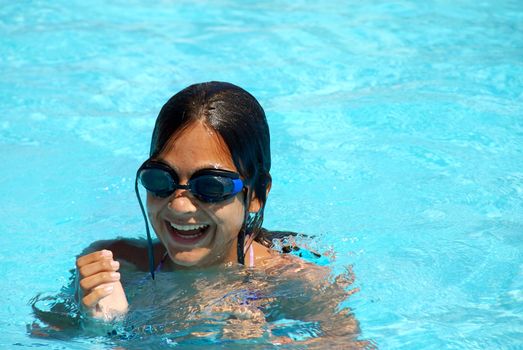 happy teen girl with goggles blue swimming pool portrait