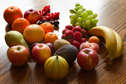 Selection of colorful, fresh, natural looking fruit on wooden background with backlight.