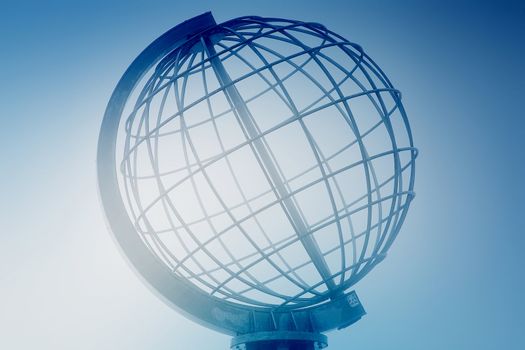 Large spiral iron globe landmark in North Norway. Globe is made of iron wire, which make up longitudes and latitudes. The globe figure is blended with a blue foggy and blurred background.