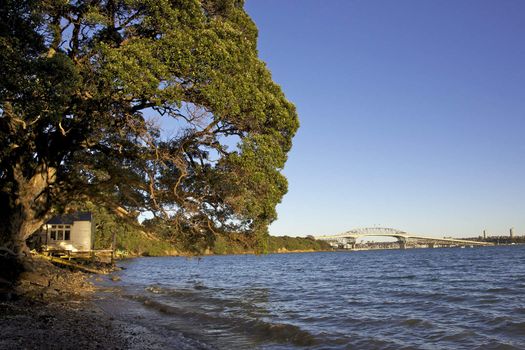 An old boathouse with Auckland Harbour Bridge in the background, New Zealand