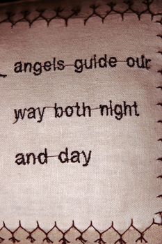 cushion embroidered with an angel quote in brown stitching