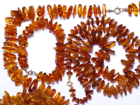 thread of amber beads on off- white background close up