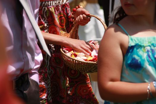 Female holding a basket full of rose petals waitng for the newly wed couple.