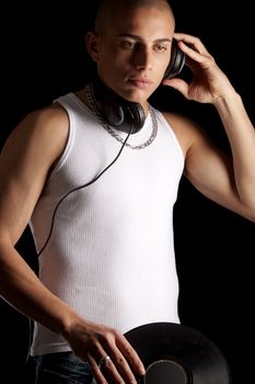 A good looking, muscular built, man on a black background with earphones.