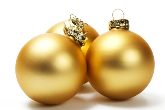 three golden dull christmas balls on white background