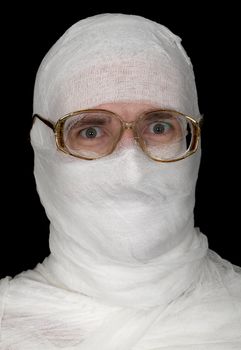 Head of the guy rolled up by bandage in spectacles on a black background