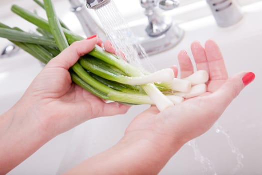 Woman Washing Onions in the Kitchen Sink.