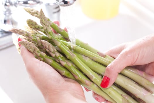 Woman Washing Asparagus in the Kitchen Sink.