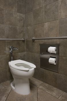 clean white toilet in a public restroom with dark stone walls