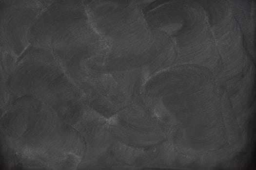 blank blackboard with swirly patterns of eraser smudges and chalk dust