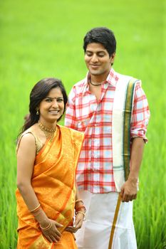 an asian couple standing in a paddy field