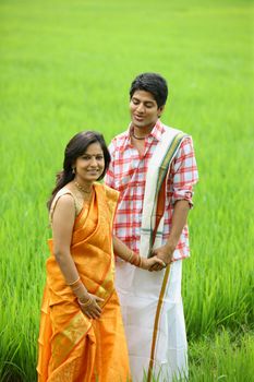 
an asian couple standing in a paddy field