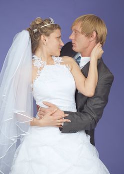 Romantic groom and the bride pose on a lilac background