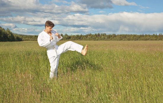 The karateka tries a kick in the field, open-air