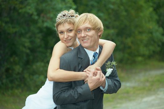 The smiling happy bride embraces the groom