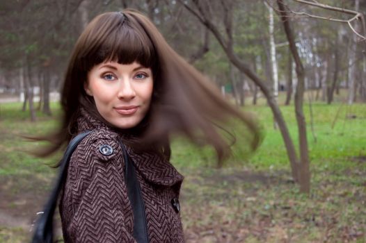 Stylish brunette with flying hair ofer early spring back