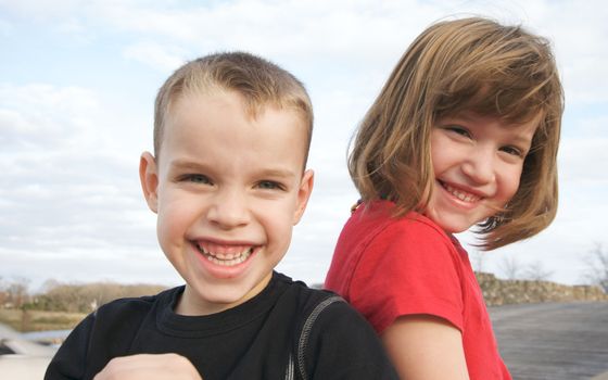 Two Children Smile for the Camera at the Park.