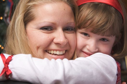 Mother and Child Hug in Front of a Christmas Tree.