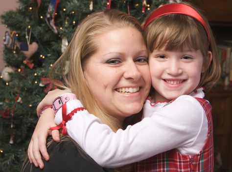 Mother and Child Hug in Front of a Christmas Tree.