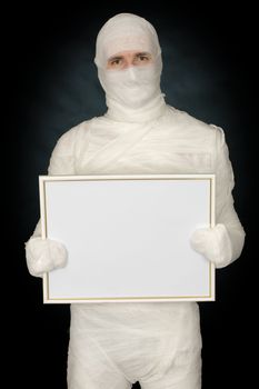 Mummy with blank frame on the black background