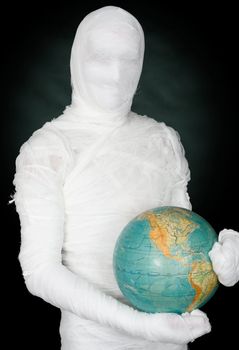 Man in costume mummy and terrestrial globe on black