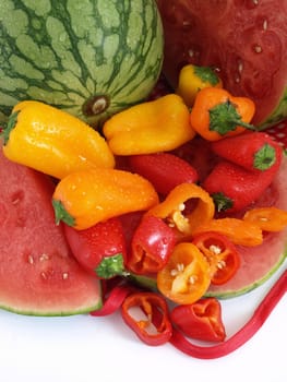 A vibrant summer crop of fresh juicy watermelon and colorful bell peppers, studio isolated over a white background.