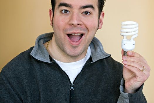 A young man holding an energy saving compact fluorescent light bulb.