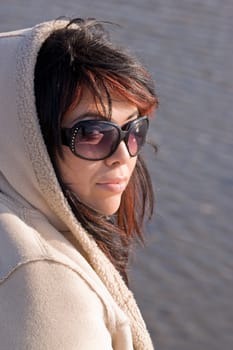 A young hispanic woman with red highlights in her hair by the sea shore.
