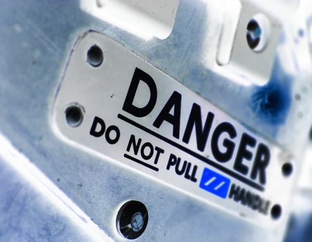 Processed photograph of a danger sign found on an old jet-fighter seat.